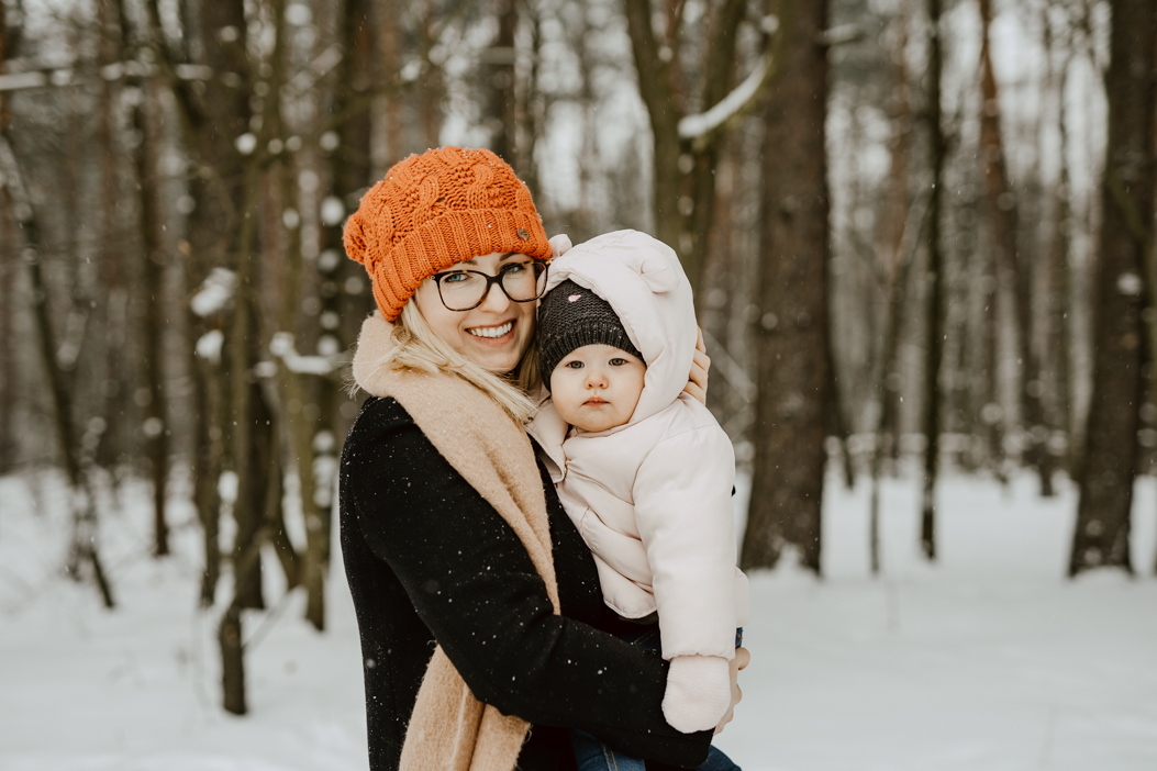 młoda mama z córeczką pozująca do sesji na śnieżnym w Puszczy Kampinoskiej
