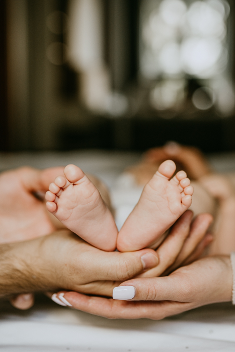 fotografia stópek niemowlaka w dłoniach rodziców zrobiona przez fotografa z warszawy 