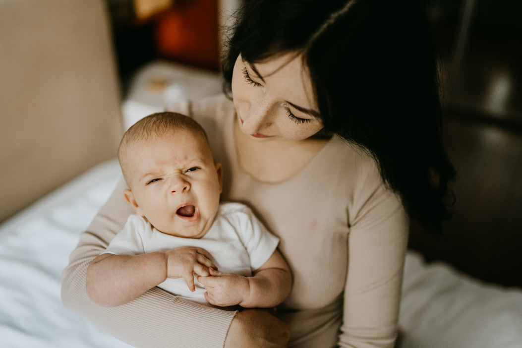 urocze zdjęcie ziewającego niemowlaka u mamy na rękach powstałe na domowej sesji niemowlęcej w warszawie 