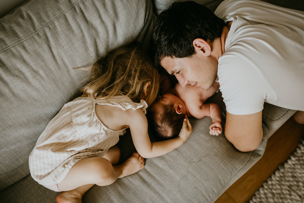 tata i córka przytulajacy się do noworodka na naturalnej sesji w domu w warszawie