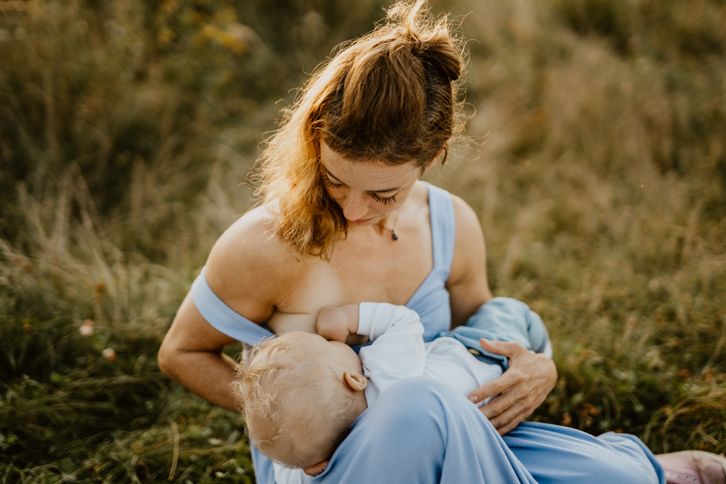 zdjecie pokazujące mamę karmiącą piersią synka w wieku niemowlęcym podczas plenerowej sesji zdjęciowej