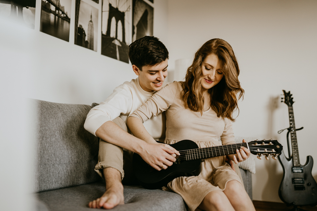 młode małżeństwo grające na ukulele podczas domowej sesji ciążowej