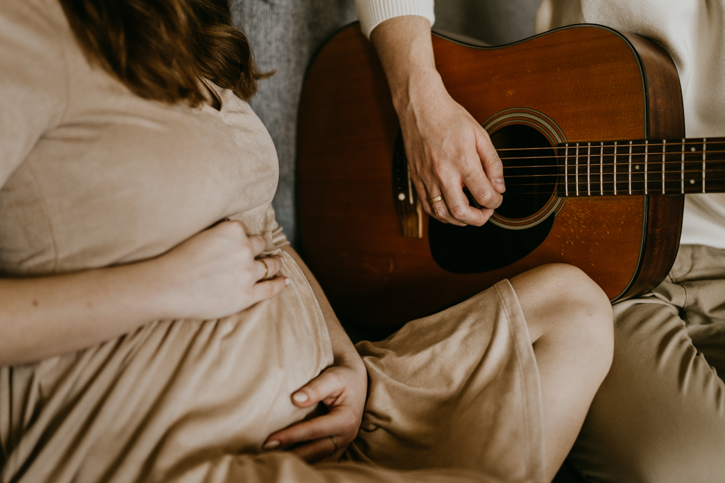 brzuch ciążowy w beżowej sukience na tle ukulele