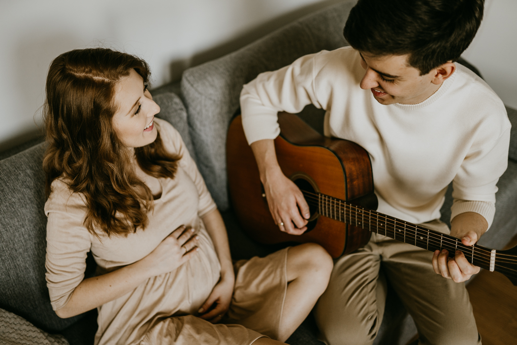 małżeństwo w ciąży mile spędzające czas w domu grając na ukulele