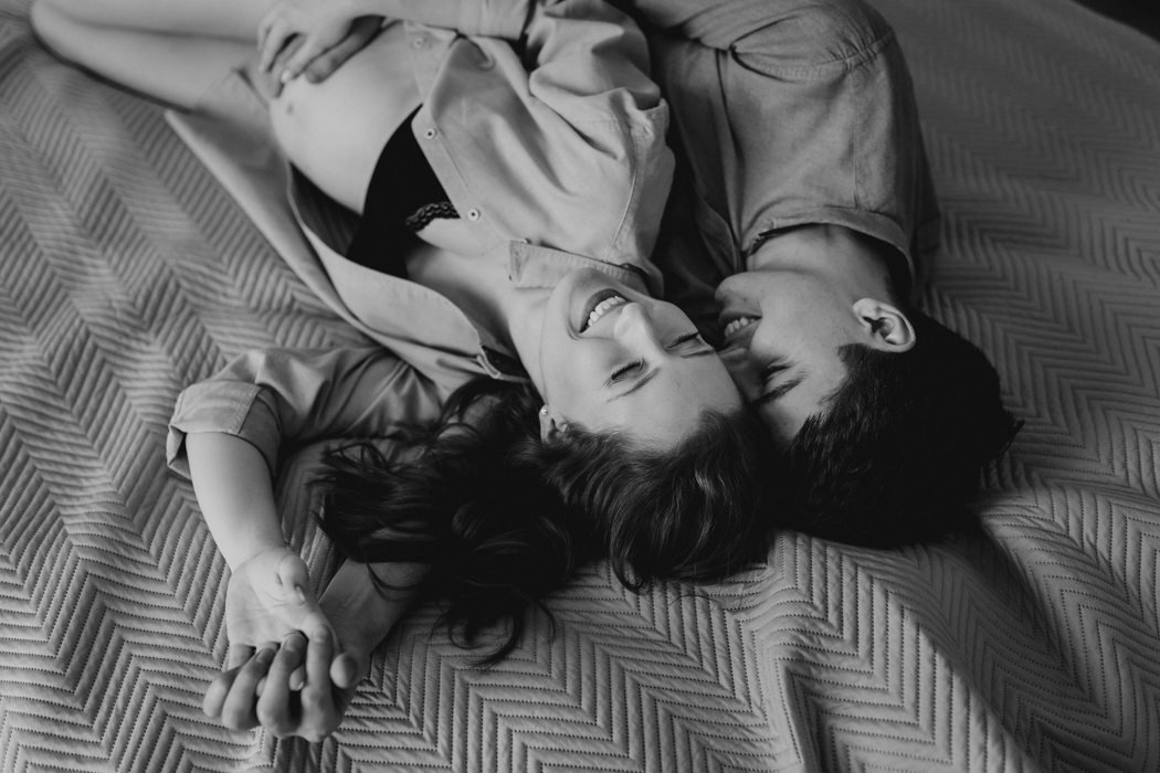 czarno biała fotografia ciążowa pary leżącej na łóżku podczas domowej sesji lifestyle