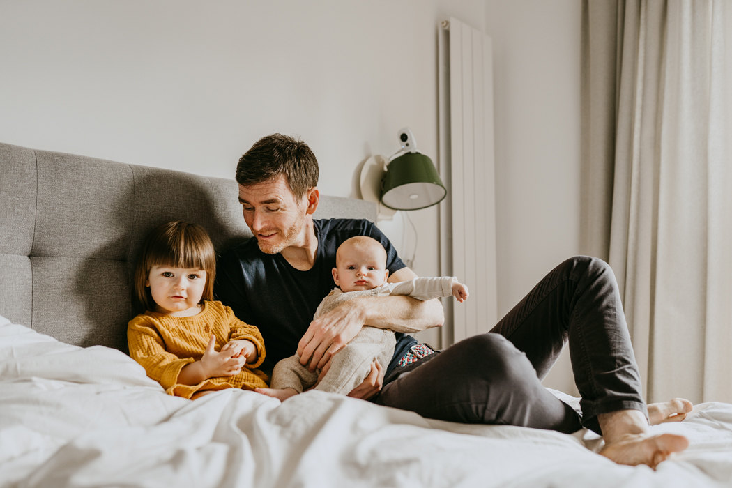 zdjęcie taty z dwójką dzieci siedzącego na łóżku wykonane na sesji rodzinnej w warszawie