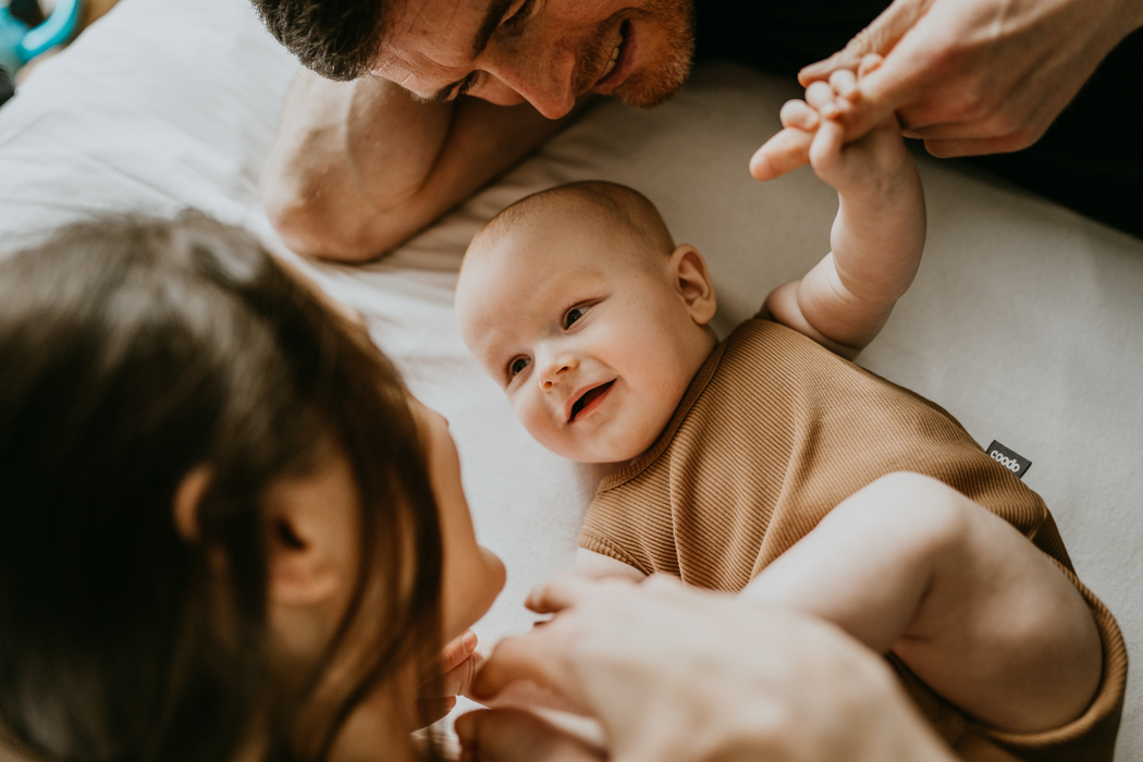 uśmiechający się niemowlak ubrany w beżowe body na sesji rodzinnej w domu w warszawie
