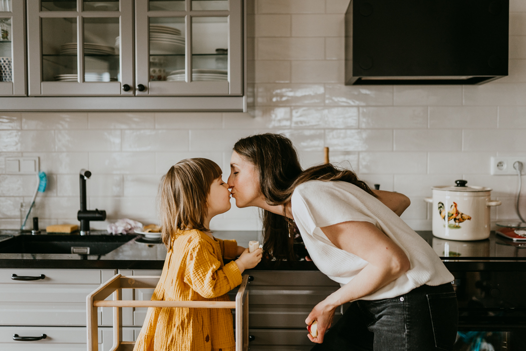 mama dająca buziaka córeczce w kuchni na domowej sesji rodzinnej