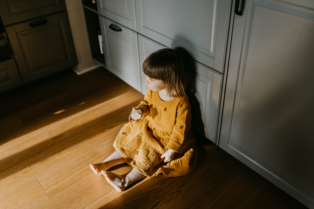 fotografia dziecka siedzącego w kuchni na które padają światłocienie, wykonana przez fotografa rodzinnego z warszawy