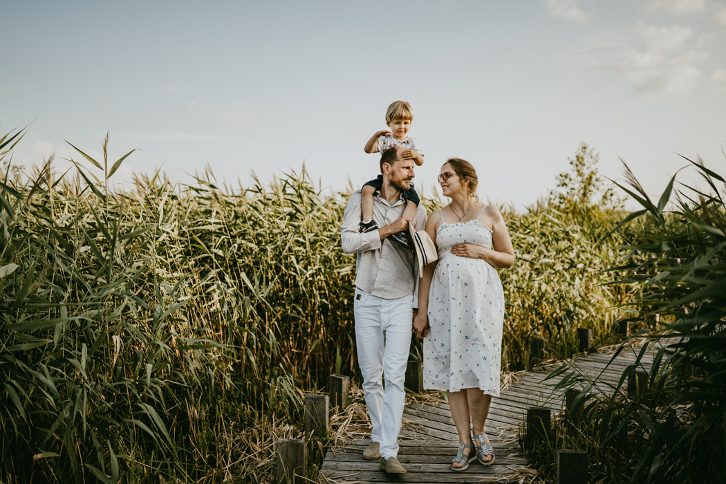 sesja ciazowo-rodzina na pomoscie i wśród dzikich traw wykonana przez fotografa rodzinnego