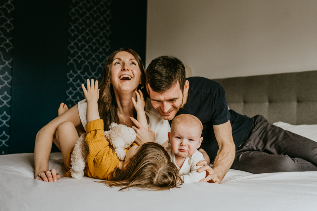 fotografia wesołej rodziny bawiącej się na łóżku z dziećmi