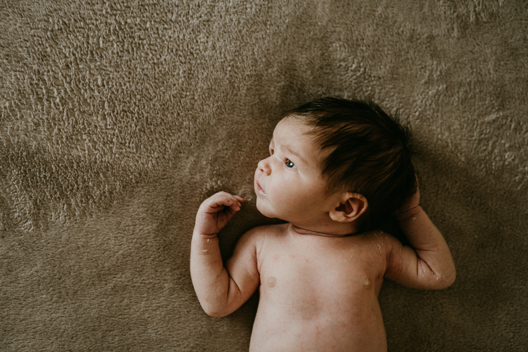 zdjęcia noworodka z długimi ciemnymi włosami w samym pampersie