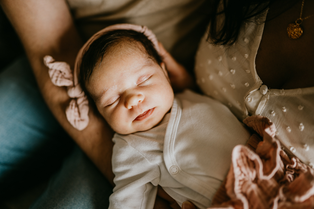 słodki śpiący noworodek w opasce z kokardką podczas sesji noworodkowej