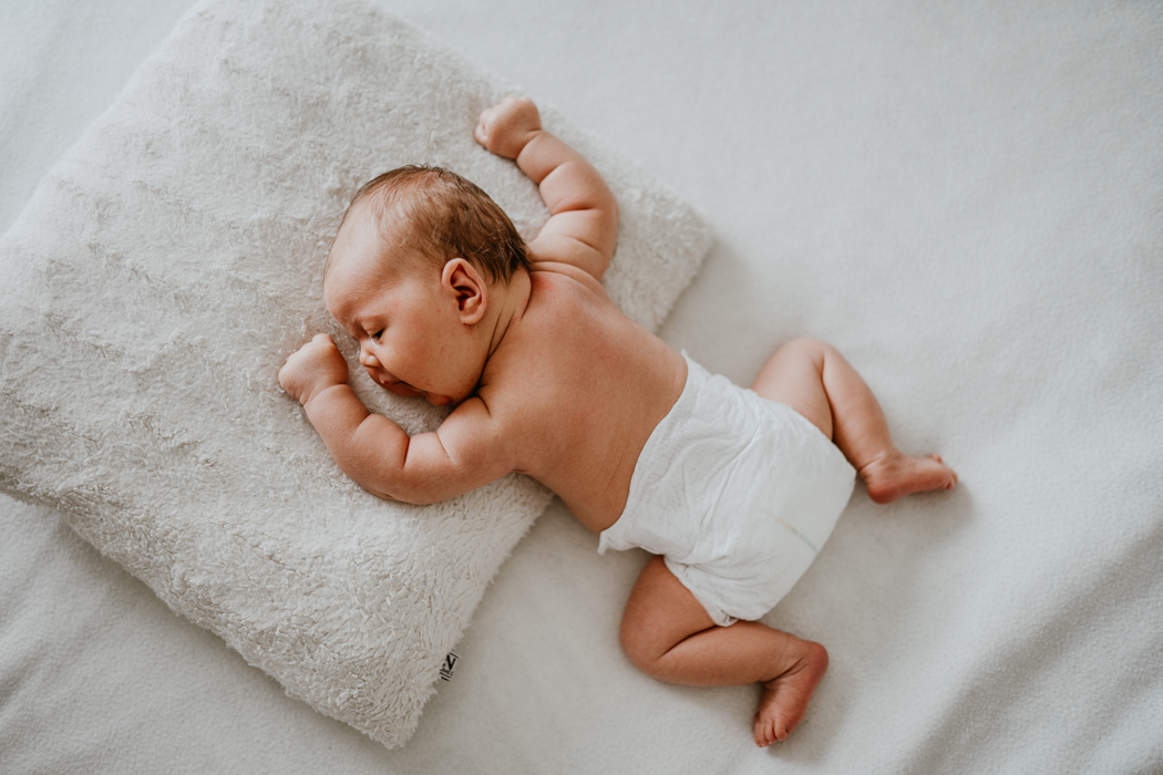 zdjecie noworodka na białej pościeli z domowej sesju lifestyle