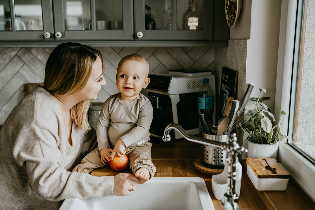 zdjęcie mamy i dziecka trzymającego w rękach jabłko i siedzącego na blacie w kuchni