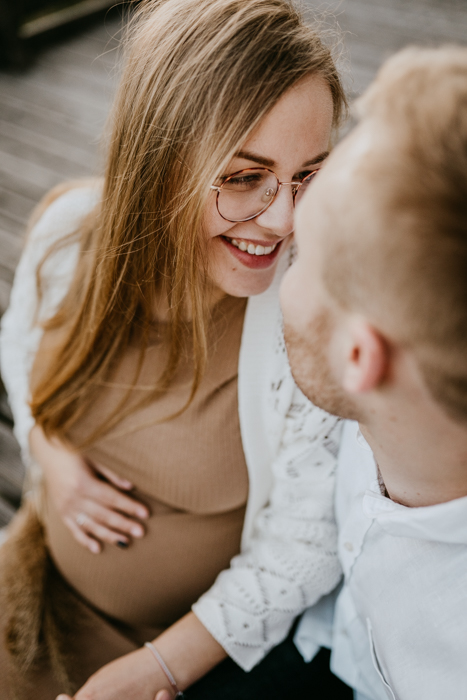 romantyczne zdjęcie kobiety patrzącej na partnera podczas sesji ciążowej