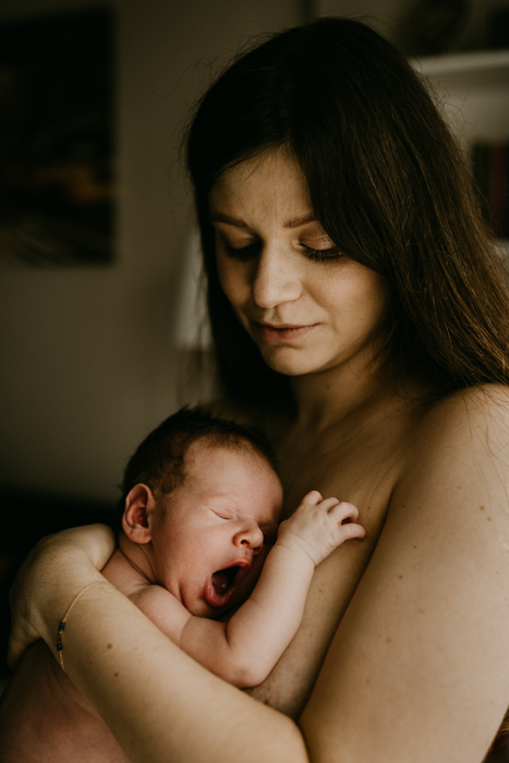 nagi ziewający noworodek przytulony do mamy