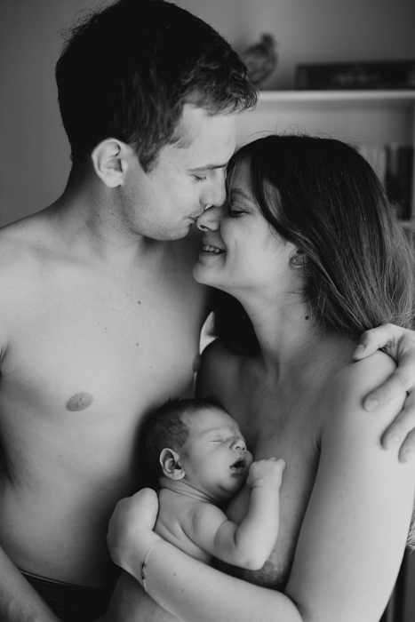 czarno-biała fotografia noworodka podczas kontaktu skóra do skóry z rodzicami podczas sesji noworodkowej w domu w warszawie