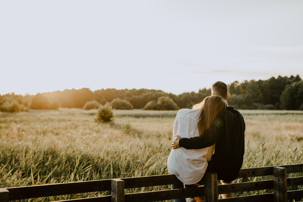 sesja narzeczeńska przytulającej się pary podczas zachodu słońca na polanie